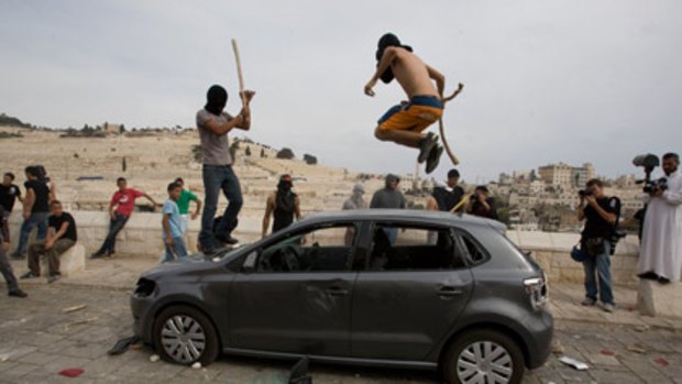 Palestinian youths destroy a car outside Jerusalem's Old City this week after a day of clashes with Israeli forces.