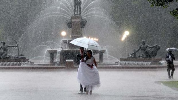 Wet, wet, wet ... Lauren and Mark Dowe came from Hobart to marry in sunny Sydney. Yesterday not one drop fell on their home town while they posed for photos in Hyde Park  beneath umbrellas.
