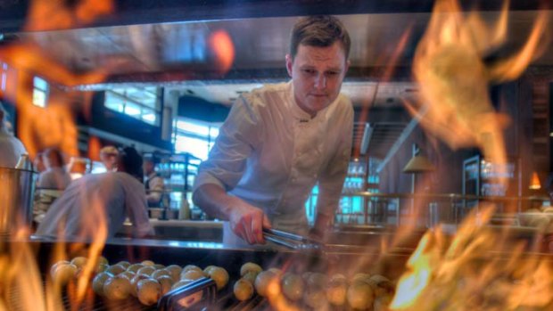 Keep the restaurant fires burning: Chef Zac Nicholson prepares meat over a grill at Neil Perry's Rockpool at Crown.