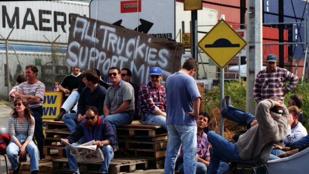 Picketers sit in front of a sign which reads "All Truckies Support MUA" at Swanson Dock, Melbourne. April 18, 1998.