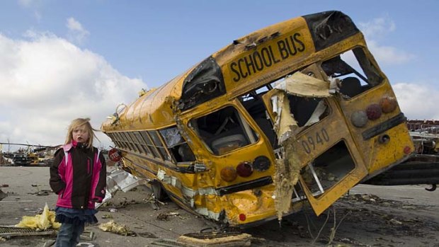 Student Madeline Evans walks past a destroyed school bus after a tornado devastated the town of Henryville, Indiana.