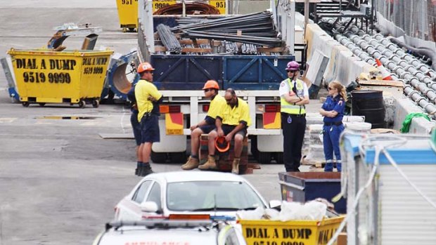 Workers sit together after a man fell to his death from scaffolding at Barangaroo.