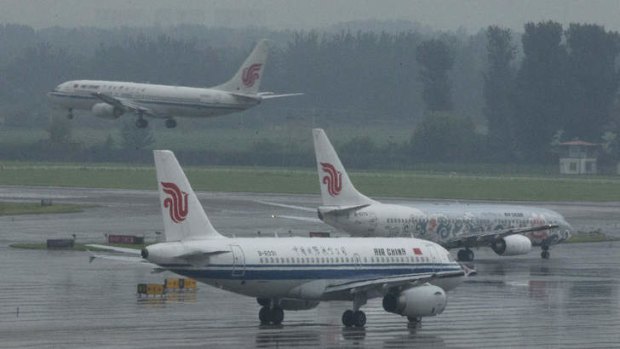 An Air China passenger plane lands while two other Air China planes wait to take off at Terminal 3 of the Beijing International Airport.