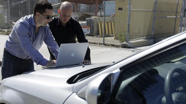 Security consultants Don Bailey, left, and Mathew Solnik, right, with iSEC Partners, demonstrate with a computer how they force cars with certain alarm systems to unlock their doors and start their engines by sending them text messages.
