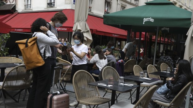 A waitress checks customers' health passes at a restaurant in Paris.