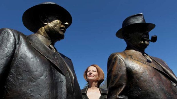 Looking for middle ground ... Julia Gillard between statues of former prime ministers John Curtin and Ben Chifley in Canberra.
