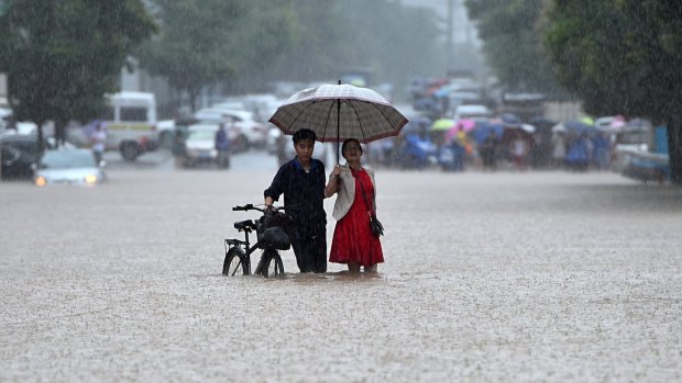A couple wade through a flooded road in Wuhan in central China.