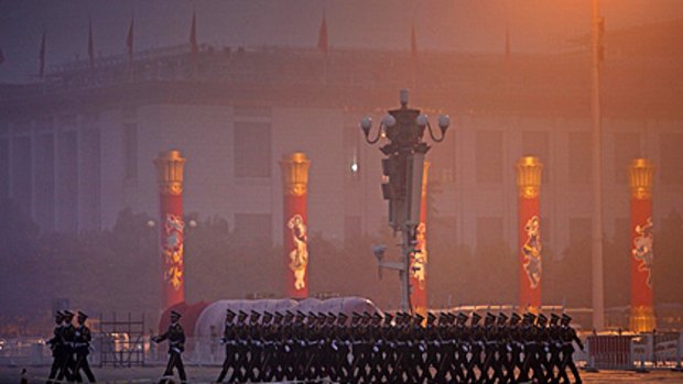 Chinese paramilitary police make their way back from the sealed-off area of Tiananmen Square after raising the flag in Beijing yesterday.