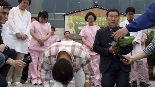 Officials kneel and bow as they apologise to victims outside the hospital in South Korea.