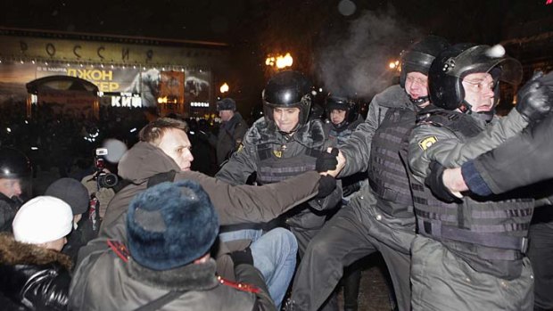 Police detain protest leader Alexei Navalny, seen wearing a hooded jacket, after a rally in Pushkin Square in Moscow.