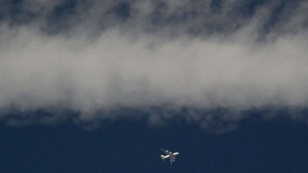 An airliner flies under smoke left by a Ukrainian military plane a few kilometres from the Russian border on July 16.