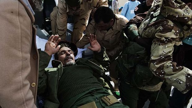 A Libyan rebel fighter is brought to the emergency entrance of Brega hospital after hurting himself with a weapon.