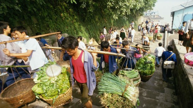 Ancient trade: workers carry baskets of produce up steps leading from the river dock in Chongqing.