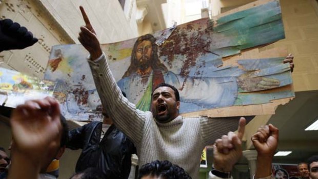 Tensions high ... Copts hold a bloodstained portrait of Jesus Christ at the Al-Qiddissine church, where 25 people were killed in a New Year's Day bombing.