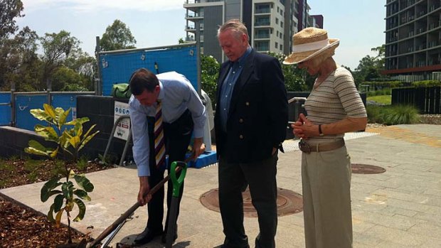 Brisbane Lord Mayor Graham Quirk plants a tree in honour of Ken Fletcher as the tennis great's long time friends Chuck and Helga Feeney look on.