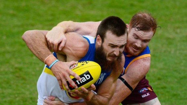 Charlie Dixon of the Suns is tackled by Daniel Merrett of the Lions.