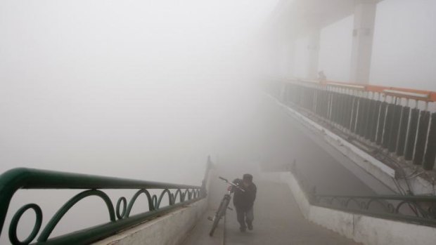 A man pushes a bike on to a bridge during a day of heavy pollution in Harbin in northeast China's Heilongjiang province.