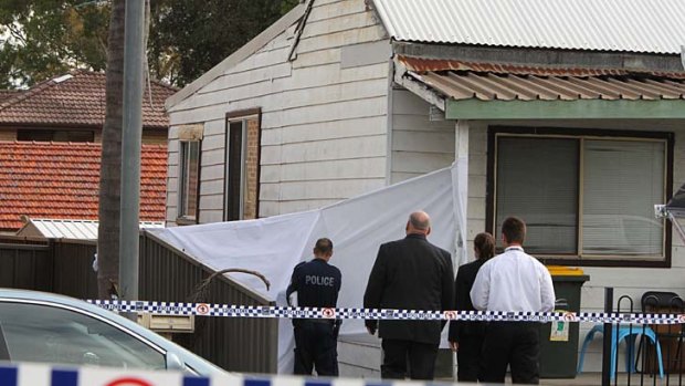 Police outside the house where two bodies were found in a garden shed.