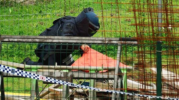 A police bomb squad officer places explosive material in the yard of a Clay St home, which was then detonated remotely.