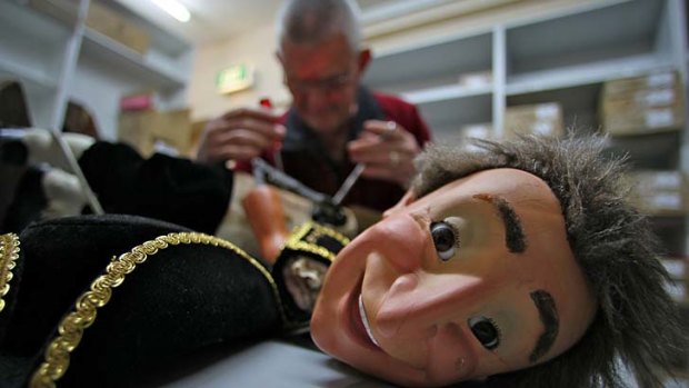 Still smiling: Repairman David Short gets Little Man back on his feet. The famous doll resides at Haigh's Chocolates in the Block Arcade.