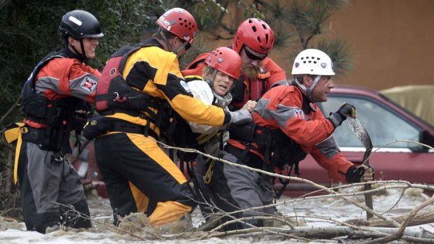 The Summit County Rescue team works to save Suzanne Sophocles, centre, from her severely flooded home  in Boulder, Colorado on  Friday.