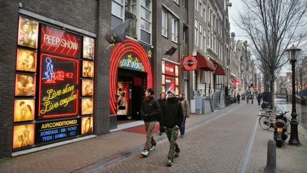 Not sexy ... tourists walks past a peep-show theatre in the Red Light district in Amsterdam.