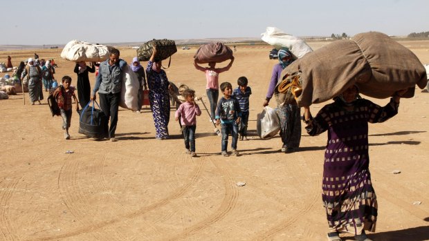 Newly arrived Syrian Kurdish refugees walk with their belongings after crossing into Turkey from the Syrian border town of Kobane on Tuesday.