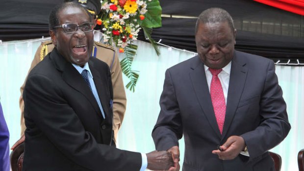 Uneasy partnership: President Robert Mugabe, left, shakes hands with Prime Minister Morgan Tsvangirai after he signed the  new constitution into law  last month.