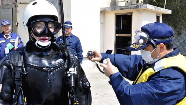 Check please ... a frogman is scanned for radiation after interrupting an undersea search at the port of Obama in north-eastern Japan.