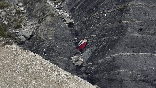 A rescue worker climbs past debris at the site of the plane crash site near Seyne-les-Alpes in France.