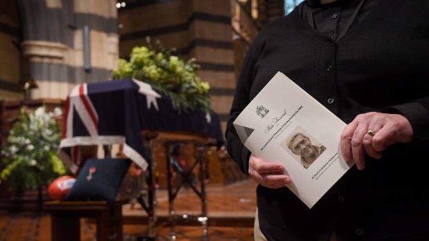A mourner holds a Lou Richards funeral program before the service.