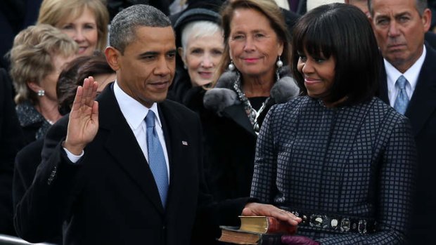 Barack Obama is sworn in during the public ceremony as first lady Michelle Obama looks on.