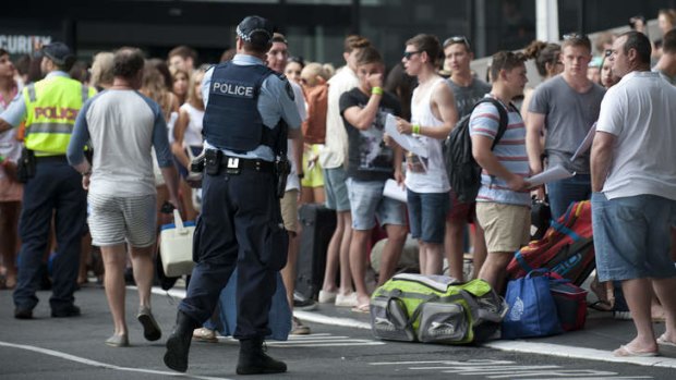 Police stand near school leavers attending the first day of Schoolies 2013 on the Gold Coast.
