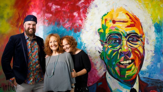 Artist Christopher Paul Toth stands with Diana and Melanie Hanna in front of a mural he painted to honour the memory of Canberra businessman John Hanna. 