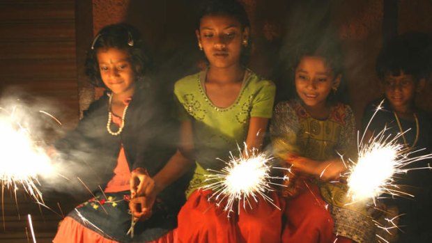 Three young Hindu girls celebrate Diwali with sparklers, India. DO NOT ARCHIVE