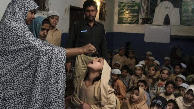 A Pakistani health worker vaccinates a schoolgirl against polio, in Karachi, Pakistan, where the disease is still endemic.