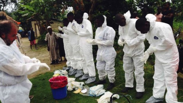 Volunteers prepare to remove the bodies of people who were suspected of contracting Ebola and died in the community in the village of Pendebu, north of Kenema, in Sierra Leone.