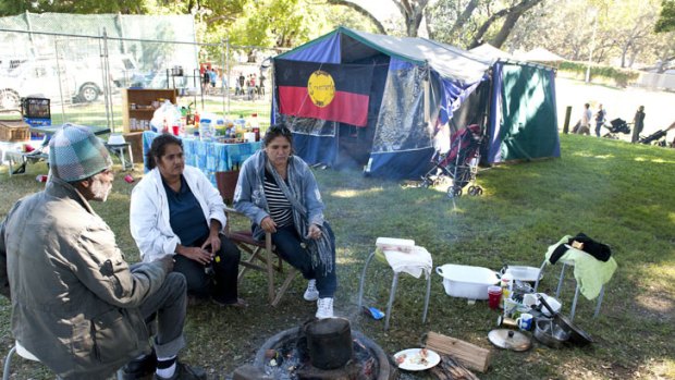 Eddie Pitt, Loulou Young and Christine Young sit in what is left of the Aboriginal Tent Embassy.