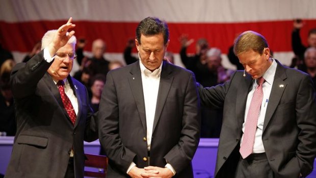 Rick Santorum, centre, receives a blessing from Pastor Dennis Terry, top left.