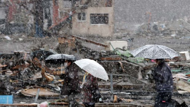 Survivors walk in the snow in  Kamaishi.