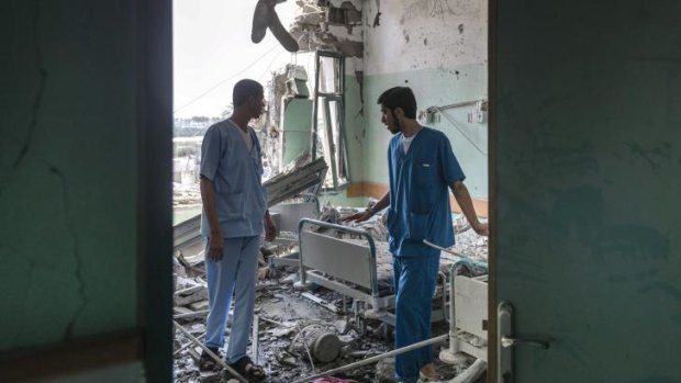 Staff members of a Deir al-Balah hospital look over the damage caused by Israeli shelling.