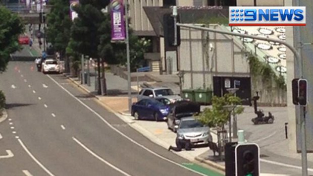 A bomb squad officer inspects three cars on Roma Street outside Brisbane's courts complex. Photo: Nine News.