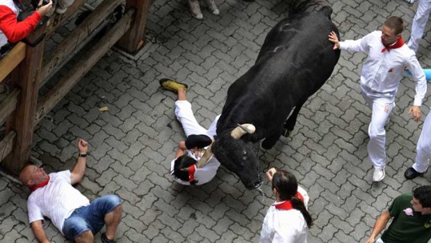 A runner is dragged by his scarf by a bull during the first running of the bulls of the San Fermin festival in Pamplona.