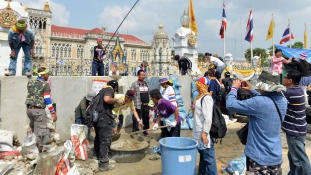 Anti-government protesters mix concrete in an attempt to build a wall in front of the gate of the Government House in Bangkok on February 17, 2014.