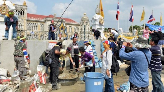 Anti-government protesters mix concrete in an attempt to build a wall in front of the gate of the Government House in Bangkok on February 17, 2014.