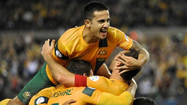 Captain's strike: Tim Cahill helps Lucas Neill celebrate on Tuesday night.