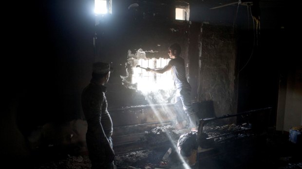 A man helps Iraqi Federal Police officers break through a wall as they inspect a former prison used by Islamic State militants in Hamam al-Alil.