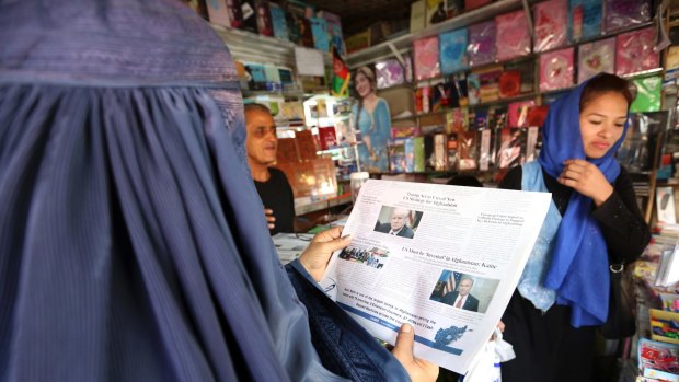 A woman reads a Kabul newspaper displaying a photo of President Donald Trump. Reversing his past calls for a speedy exit, Trump has recommitted the US to the 16-year-old war in Afghanistan.