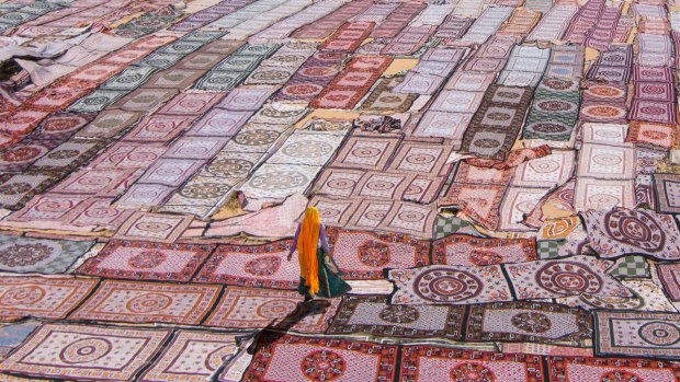 Rugged landscape: A woman walks across a sea of traditional rugs laid out to dry in a village in India's north-west desert region of Rajasthan. 