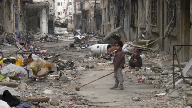 A child clears damage and debris in the besieged area of Homs.